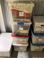 Four transparent storage containers stacked, showing various fabrics inside with some labels and handwritten stickers