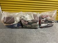 Front view showing three large clear plastic bags filled with miscellaneous fabric pieces packed and compressed inside.