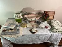 Overview of multiple table decor items on table including centerpieces, candles, placemats, and small art