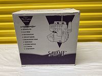 Box front side showing Savant serger model and some features like LCD screen, differential feed, color-coded threading, accessory storage, and 10-year warranty.
