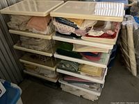 12 plastic project boxes stacked containing assorted small fabric pieces in various colors and patterns.