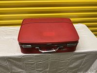 Small vintage red American Tourister suitcase with silver hardware and handle, front and top view.