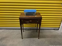 Front view of wooden sewing cabinet with plastic tote on top