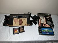 Atari 2600 console with joysticks, paddles, two games (Combat and Ms. Pac-Man), owner's manual, and Microvision handheld game console with game cartridge Box.
