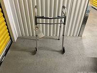 Photo of metal walker with two front wheels and height adjustment feature.