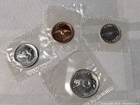 Four Canadian coins individually sealed in plastic sheets with clear views showing the obverse and reverse sides in gem mint condition.