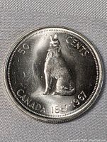 Front side of the 1967 Canadian silver half dollar showing a seated howling wolf and inscriptions 50 Cents, Canada 1867-1967.