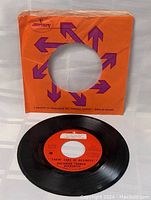 Front view of orange Mercury paper sleeve with purple arrows design. The sleeve has a center hole showing the vinyl record label through it.