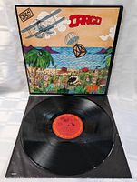 Vinyl record partially removed from sleeve showing red center label and visible condition of vinyl surface.