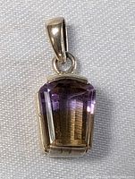 Close-up front view of the sterling silver pendant with large faceted amethyst stone resting on a light fabric background.