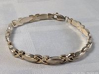 Sterling silver vintage bracelet arranged in circular shape on white fabric background showing front links and overall design