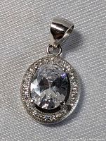 Close-up photo of the sterling silver oval pendant with clear faceted crystal center and halo of smaller crystals, set in polished silver with bail.