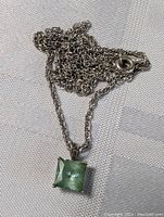 Photo of tangled sterling silver chain and attached emerald green square pendant showing pendant clarity and clasp.