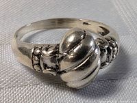 Front angle showing the knotted design and decorative scroll details on sterling silver ring.