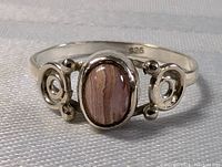 Close-up front view of the sterling silver ring with oval tourmaline stone, showing swirl designs and 925 stamp inside the band.