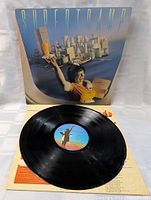 Vinyl LP record placed outside album cover. Shows the black disc with colorful center label and album cover artwork. Vinyl looks clean and playable.