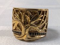 Full front view of vintage gold plated ring showing the tree relief motif and emerald stones