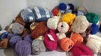 Overall view showing a variety of yarn balls and skeins in different colors and textures, including packaged and loose yarns.