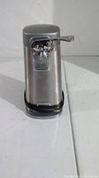 Front view of the Cuisinart stainless steel electric can opener showing the lever, cutting mechanism, and base.