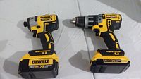 Both DeWalt cordless tools side by side on white background with batteries attached