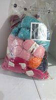 Large clear plastic bag containing multiple small skeins of assorted yarn in colors including burgundy, turquoise, pink, orange, red and blue