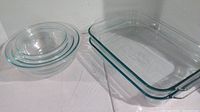 Photo showing 4 clear glass nesting mixing bowls stacked together and 2 rectangular clear glass baking dishes stacked beside them.