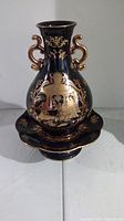 Photo of black and gold Satsuma style two-handled urn with decorative painted scene and motifs