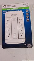 Photo of first Commercial Electric Swivel Surge Protector in original packaging showing front with outlets, USB symbols, and product details.