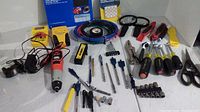 Wide view of lot showing rotary tool, safety goggles, wire coil, screwdriver bits, drill bits, hand tools, and screwdrivers.