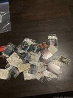 Overview of vintage 1988 WWF Hostess WrestleMania IV stickers scattered on wooden surface, mostly inside small clear plastic sleeves, showing wrestler images and event branding.