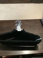 Top angle photo showing the bundle of black felt clothes hangers with silver metal hooks stacked together.