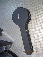 Black Gruv Gear branded hard case for a banjo, shaped to fit a banjo with silver latches and side handle, lying on a gray diamond plate background.