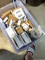 Image showing plastic container filled with assorted boxed HALO 4-inch recessed pot lights and other electrical components.