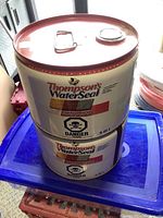 Two stacked metal cans of Thompson's WaterSeal Clear Multi-Surface Waterproofer, size 9.45L each, with hazard poison labels.