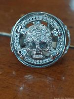 Close up image of the silver-tone spinner ring with rhinestone skull and crossbones design.