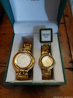 Pair of Delmon Super Deluxe quartz watches in a green presentation box, showing both watches side-by-side from above with visible faces and bands