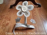 Front view of the handcrafted Inuit daisy flowers sculpture showing the large central flower with six petals and two smaller flowers mounted on thin stems on a curved base.