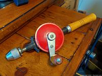 Photo of the vintage mechanical hand drill showing red gear housing and wooden handle