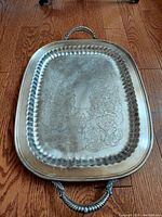 Top view of vintage rectangular silver plated serving tray with ornate handles and decorative etched floral pattern on surface, showing overall condition and details.