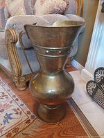 Front view of large hammered brass container with cobra-shaped handle, showing rounded base and flared top opening.