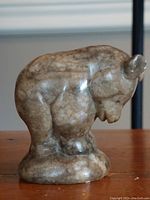 Side view of the soapstone bear cub showing the curved posture and textured stone finish.