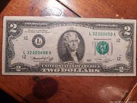 Front side of vintage US 1976 two-dollar bill with Thomas Jefferson's portrait, visible serial number, and treasury signatures.