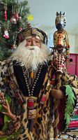Close-up of the African Santa figurine head and upper body showing the detailed face, white beard, multicolored headdress, and wooden beaded necklace.