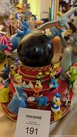 Snow globe on birthday cake base with Disney character figurines: Genie, Dumbo, Goofy, Donald Duck, and others.