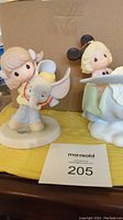 View of two Precious Moments Disney Dumbo collectible figurines side by side on a table with auction number card.