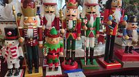 Front view of the nine nutcracker figurines showing their varying heights and festive detail with elf, snowman and king prominently visible.