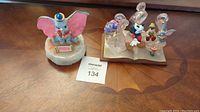 Two Disney sculptures side by side on wood surface: Dumbo figurine and a Disney character resin sculpture.