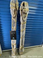 Two tall wood carvings wrapped in bubble wrap and taped, positioned upright against a blue door.