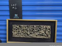 Full frontal view of the carved wood panel in its rectangular frame