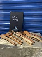 Lot of 10 assorted wooden kitchen utensils displayed on fabric-covered surface against corrugated metal background, showing variety of spoon and spatula shapes and woods.